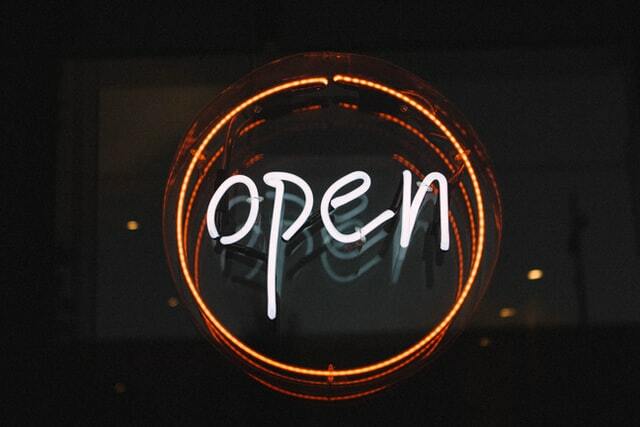 Rundes neonfarbenes Schild mit der leuchtenden Aufschrift Open